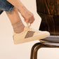 NGO SHOES Handgemachte beige Sneaker mit braunem Ethno-Muster, getragen von einer Person, die die Schnürsenkel bindet.
Nachhaltige und vegane Fair-Trade-Schuhe auf einem stilvollen Holzstuhl.