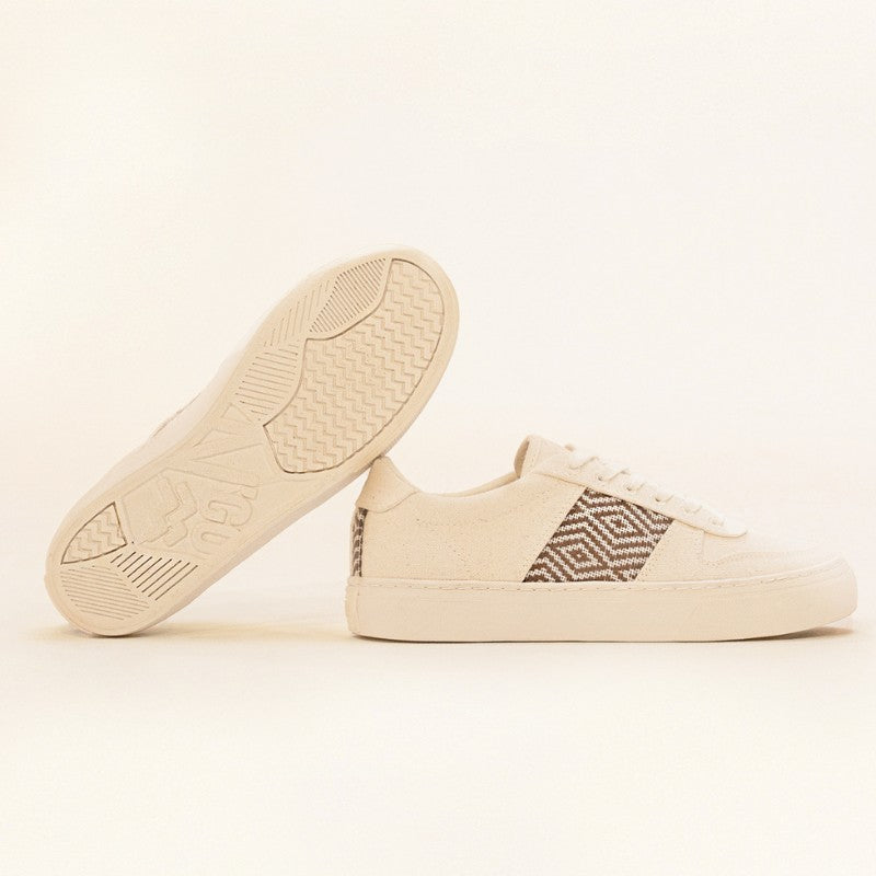 Beige Sneaker auf hellem Hintergrund – eine Schuhsohle sichtbar, die andere zeigt das detailreiche Ethno-Muster.
Vegane Lifestyle-Sneaker mit nachhaltiger Sohle und traditioneller Webkunst.
