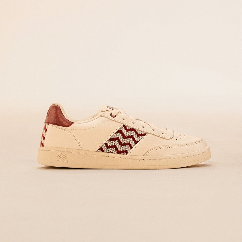 Nachhaltige Sneaker aus beigem Leder mit bordeauxfarbenem Ethno-Muster und weißer Sohle – handgefertigt in Vietnam.